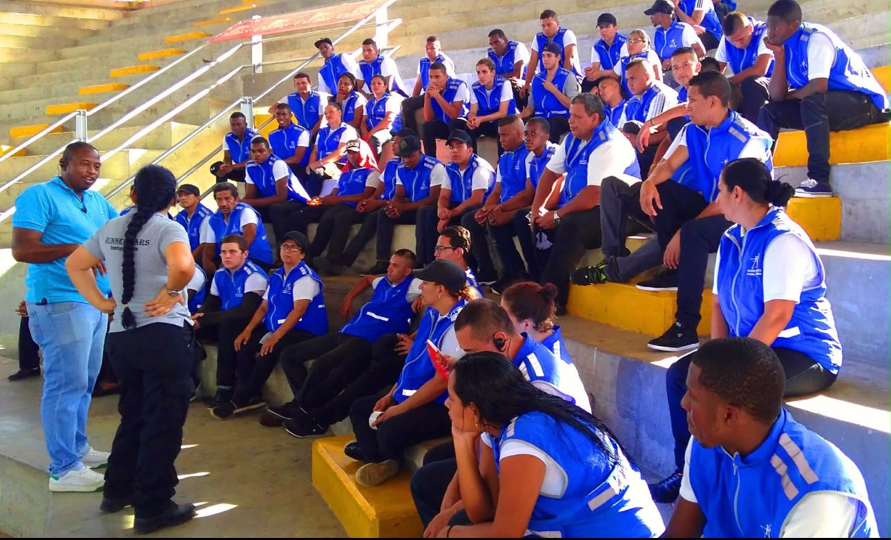 Integrantes del equipo con chalecos azules participan en una sesión de formación en gradería